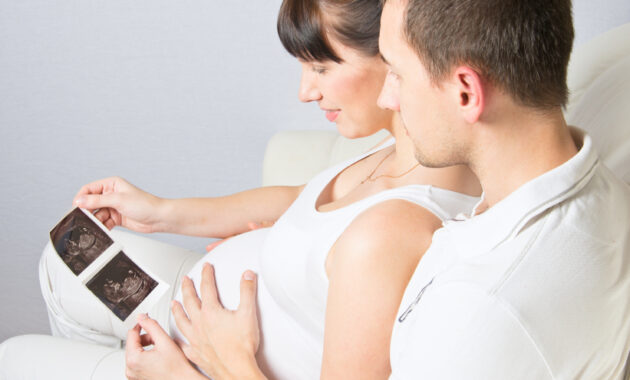 Young couple looking at their baby ultrasound picture