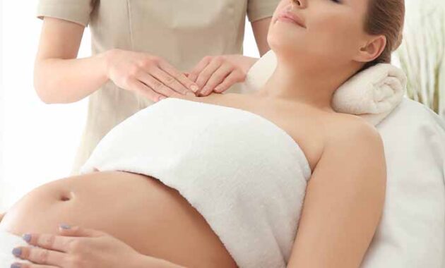 Young beautiful pregnant woman having massage in spa salon